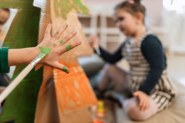 A close-up of little girl painting with brush on her hand during art class.