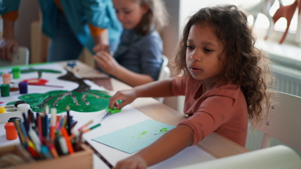 A group of little kids working on project with teacher during creative art and craft class indoors at school.