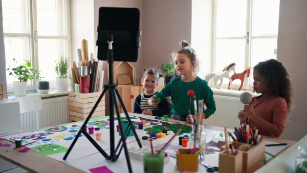 Happy little girls painting a picture during creative art and craft class at school.