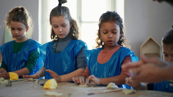 A group of little kids with teacher working with pottery clay during creative art and craft class at school.