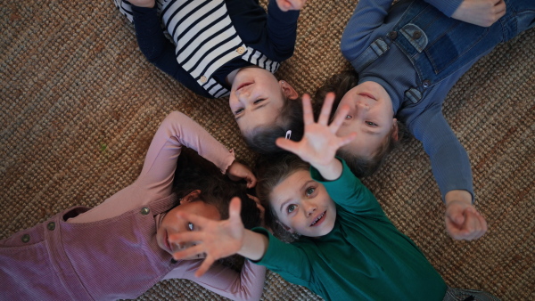 A top view of of little girls friends lying on back on floor and having fun