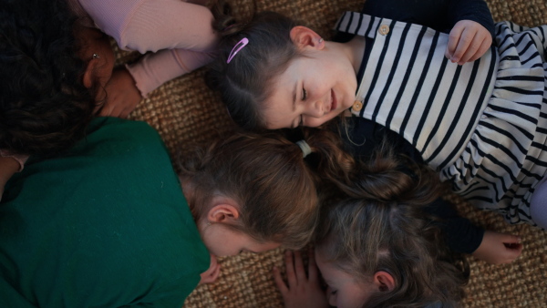 A top view of of tired little girls friends lying on back on floor and sleeping.