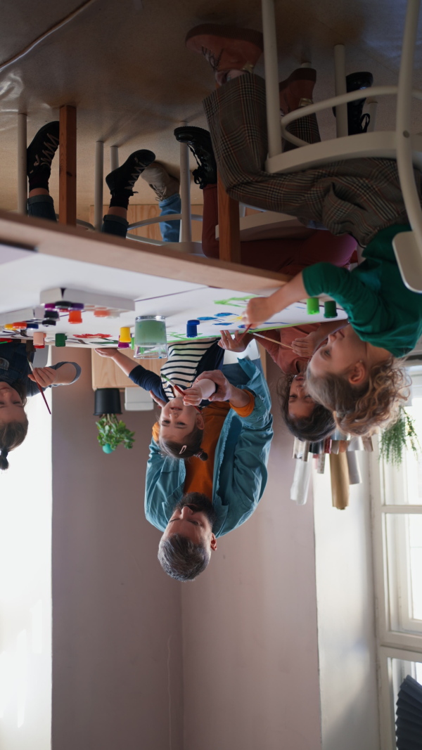 A vertical footage of little kids working on project with teacher during creative art and craft class at school.