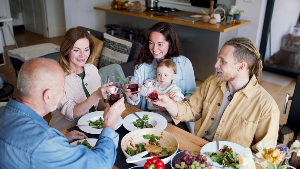 A happy multigeneration family indoors at home eating healthy lunch, having good time.