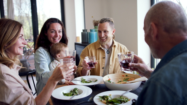 A happy multigeneration family indoors at home eating healthy lunch, having good time.