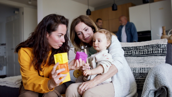 A happy multigeneration family playing with small baby indoors at home, visiting concept.