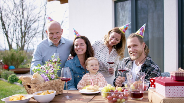 A happy multigeneration family outdoors in garden at home, birthday celebration party.