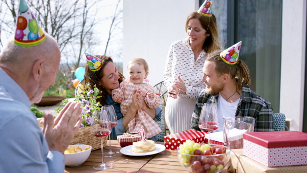 A happy multigeneration family outdoors in garden at home, birthday celebration party.