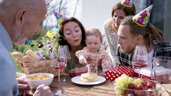 A happy multigeneration family outdoors in garden at home, birthday celebration party.