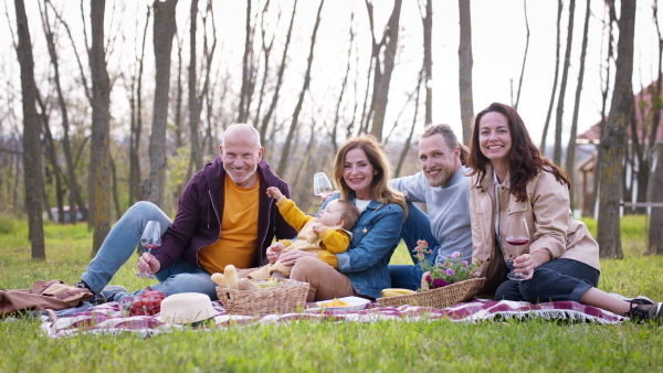 A happy multigeneration family outdoors having picnic in backyard garden, looking at camera.