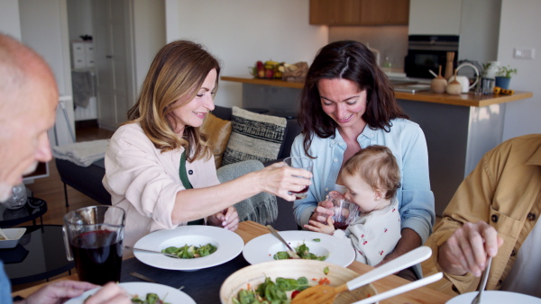 A happy multigeneration family indoors at home eating healthy lunch.