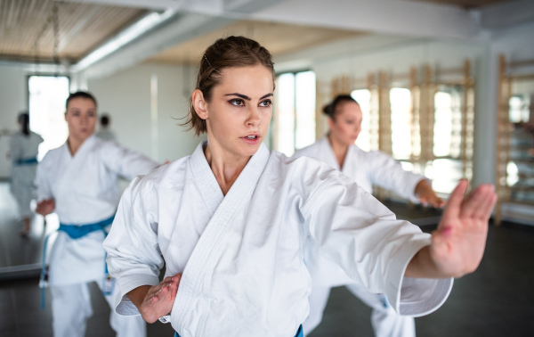 A group of young women practising karate indoors in gym.