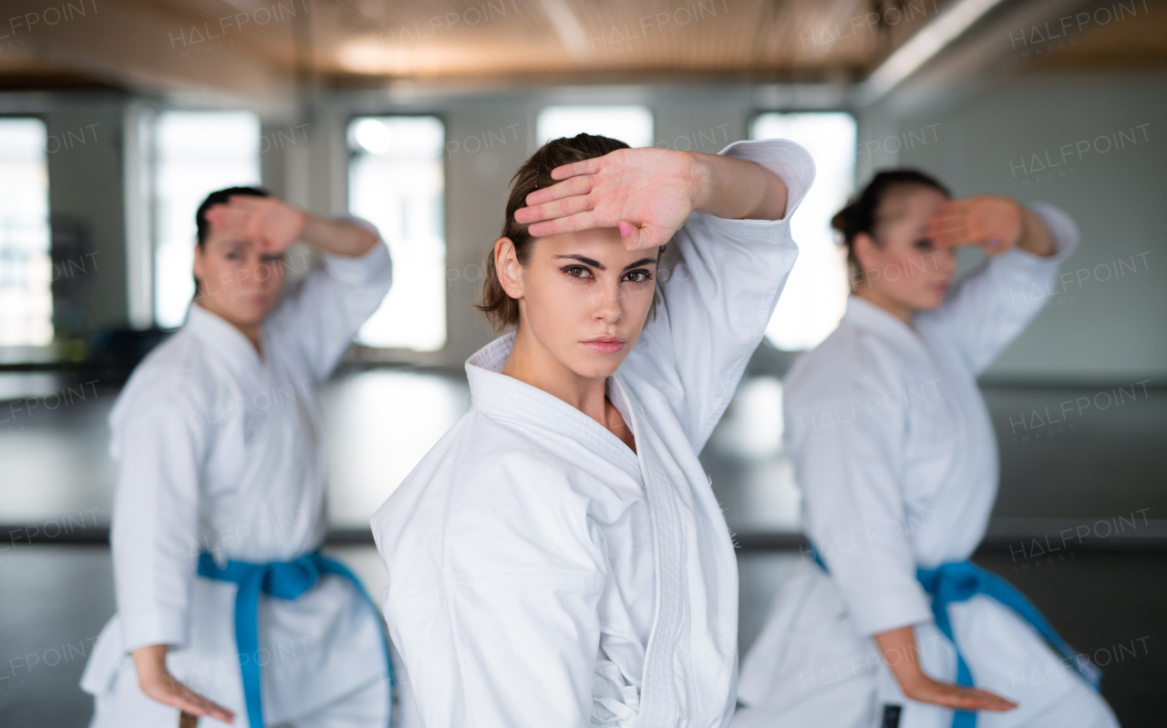 A group of young women practising karate indoors in gym.