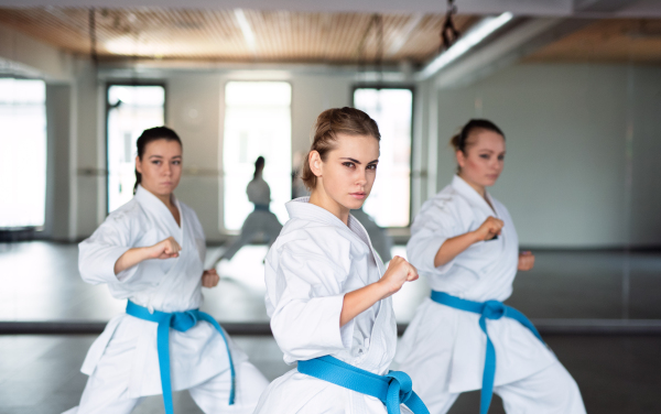 A group of young women practising karate indoors in gym.