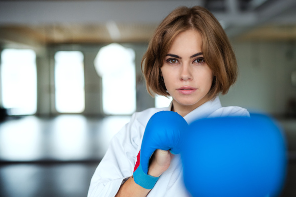 An attractive young woman practising karate indoors in gym.