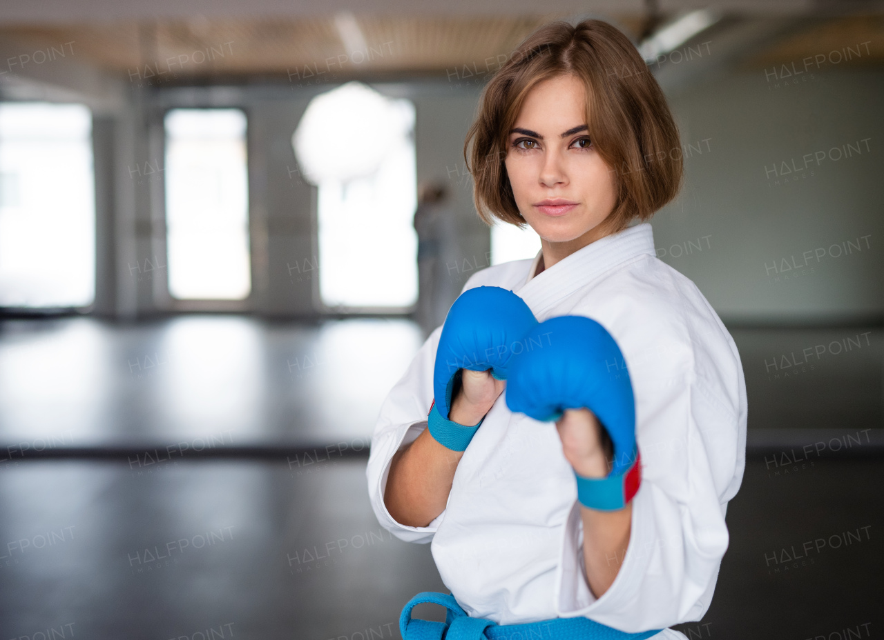 An attractive young woman practising karate indoors in gym.