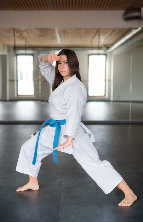 An attractive young woman practising karate indoors in gym.