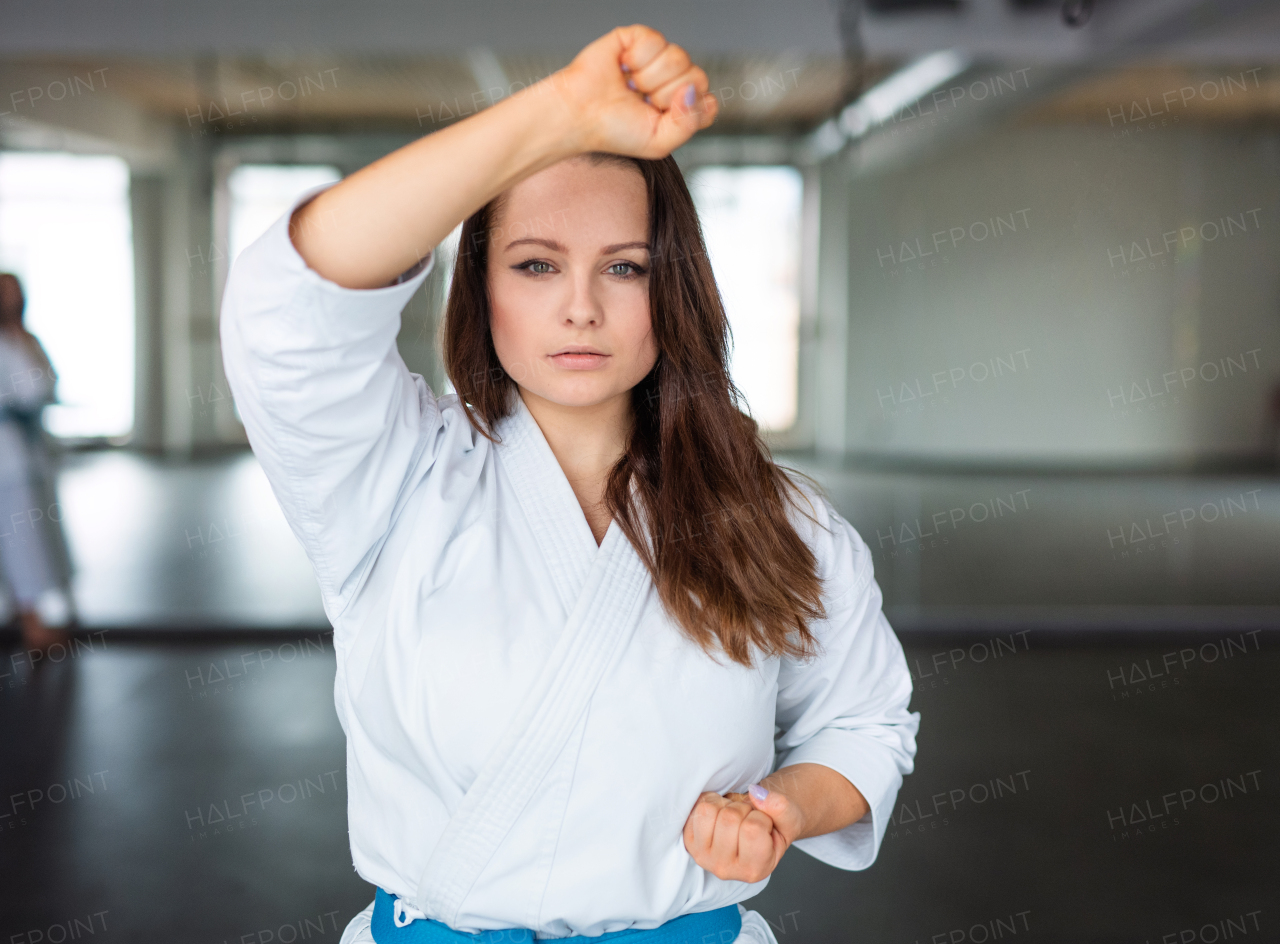 An attractive young woman practising karate indoors in gym.