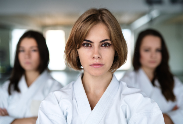 A group of young women practising karate indoors in gym.