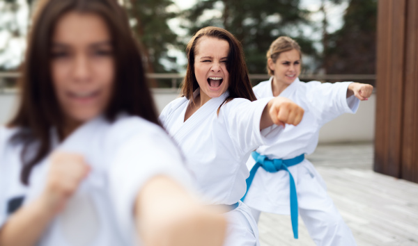 A group of young women practising karate outdoors on terrace.