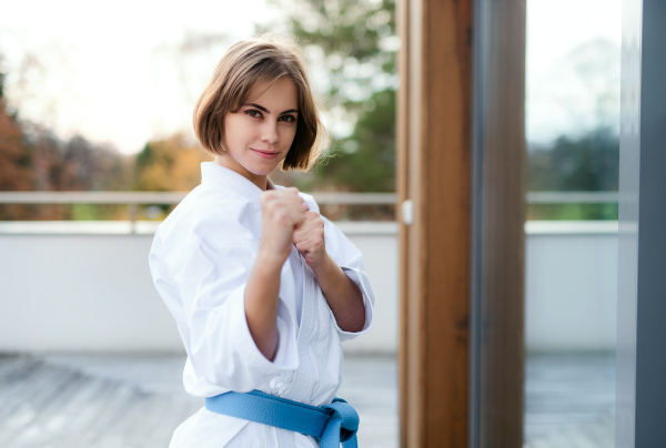 An attractive young woman practising karate outdoors on terrace.