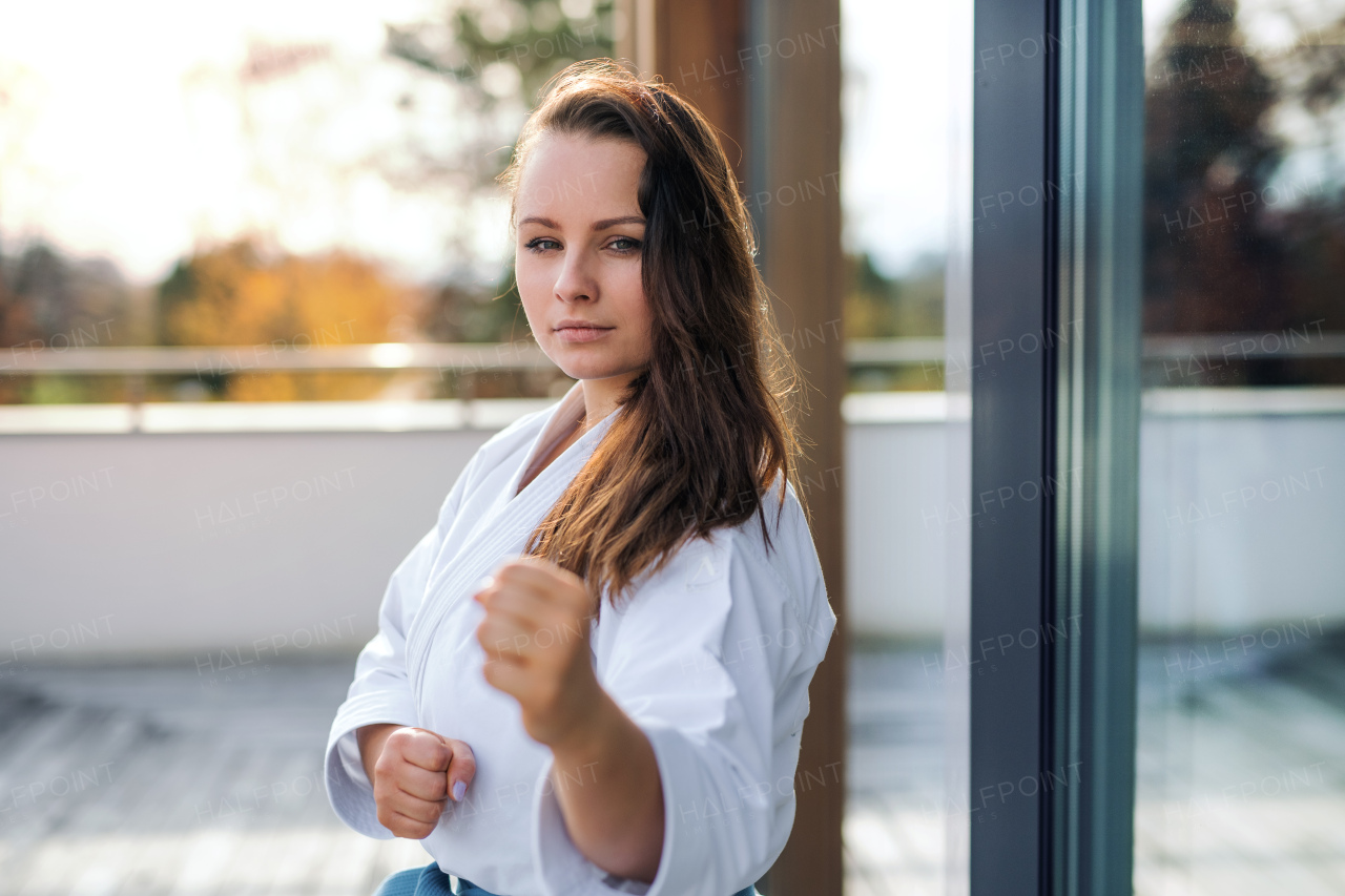 An attractive young woman practising karate outdoors on terrace.