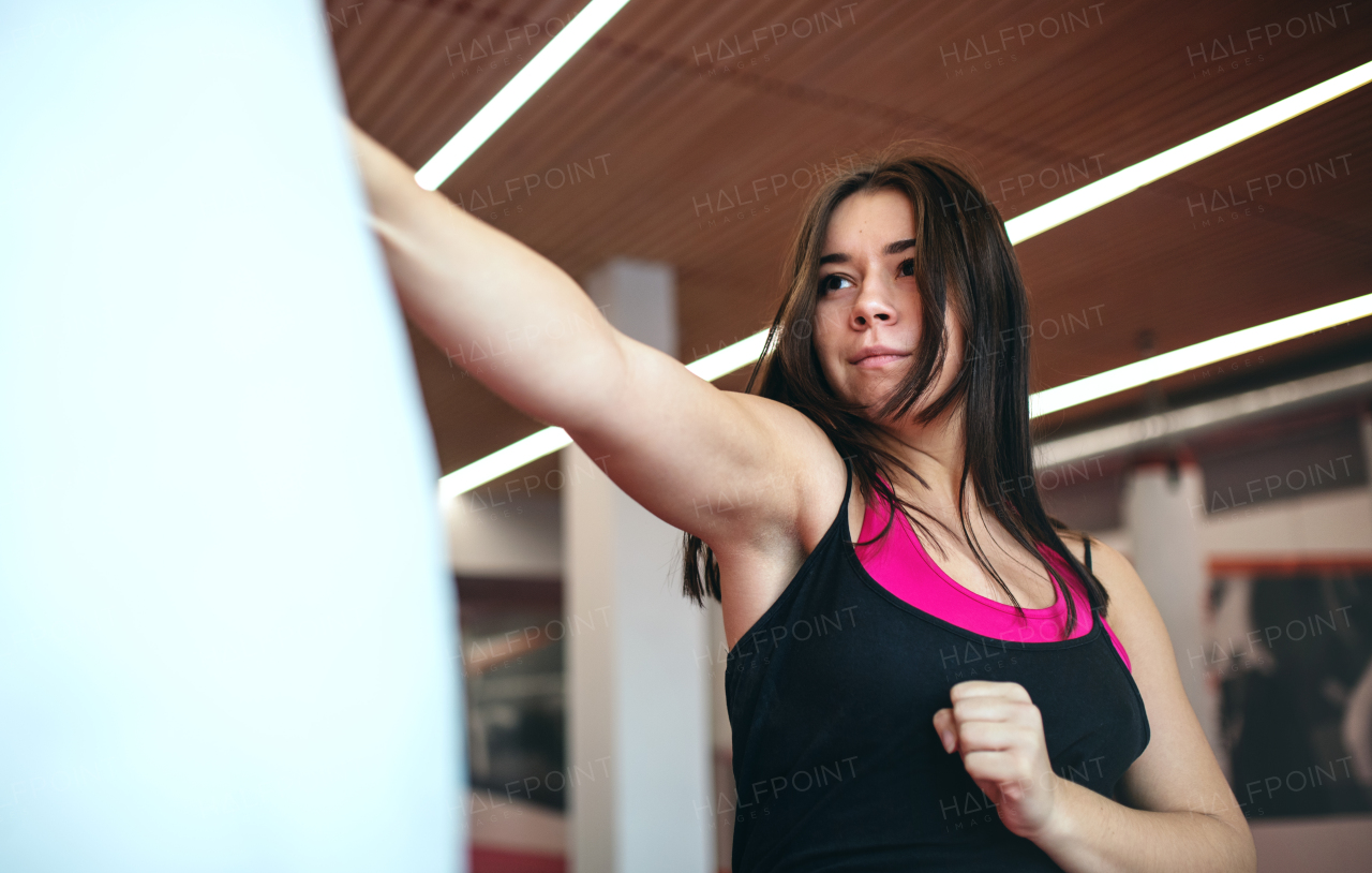 An attractive young woman practising karate indoors in gym. Copy space.