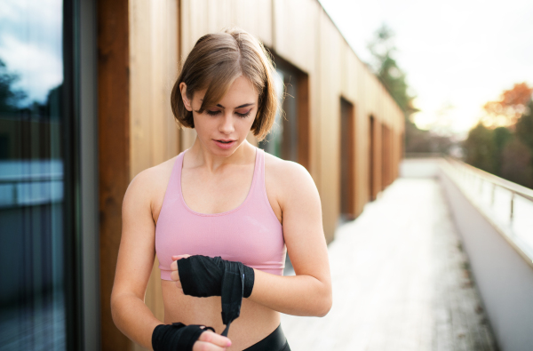 A front view of young woman practising karate outdoors on terrace.