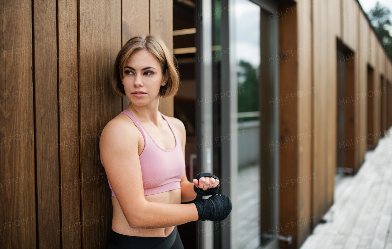 A young sportswoman standing outdoors on terrace, resting. Copy space.