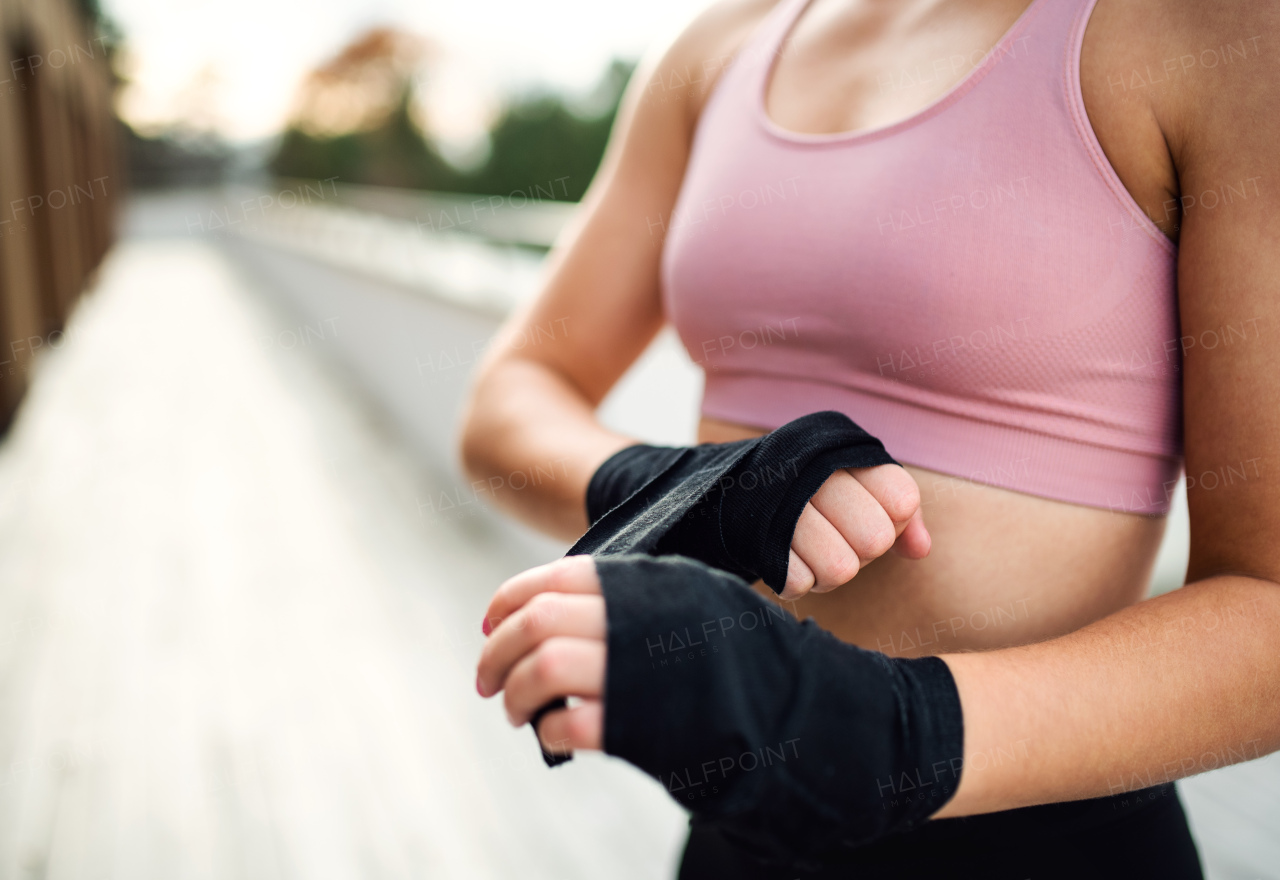 A midsection of young sportswoman standing outdoors on terrace, resting. Copy space.