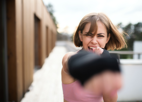 A front view of young woman practising karate outdoors on terrace.