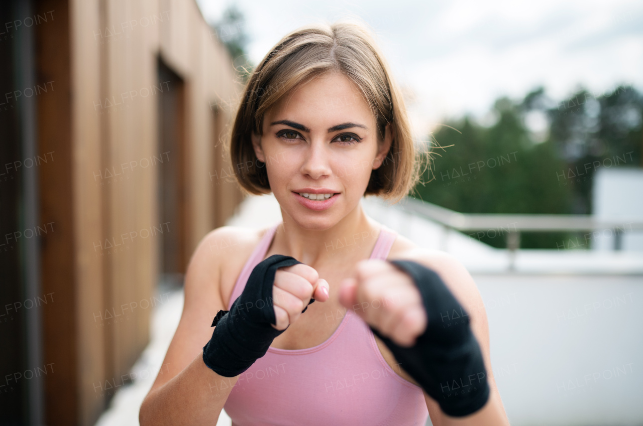 A front view of young woman practising karate outdoors on terrace.