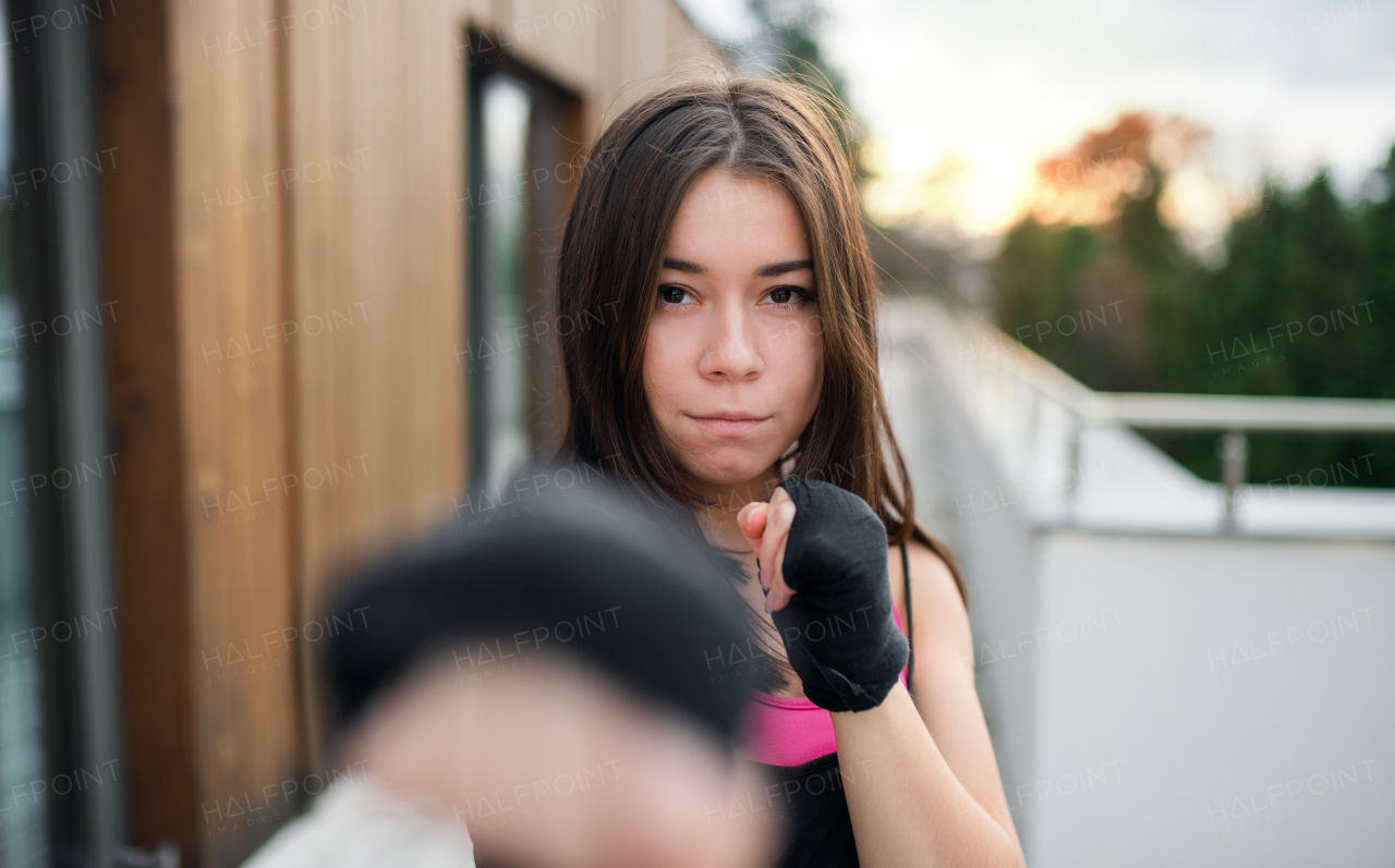 A front view of young woman practising karate outdoors on terrace.