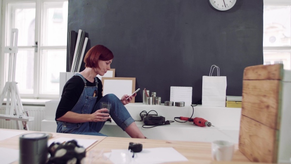 Young woman using smartphone indoors, old furniture restoration.