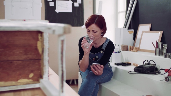 Young woman using smartphone indoors, old furniture restoration.