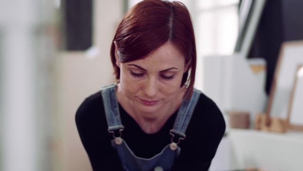 A front view portrait of young woman with smartphone indoors.