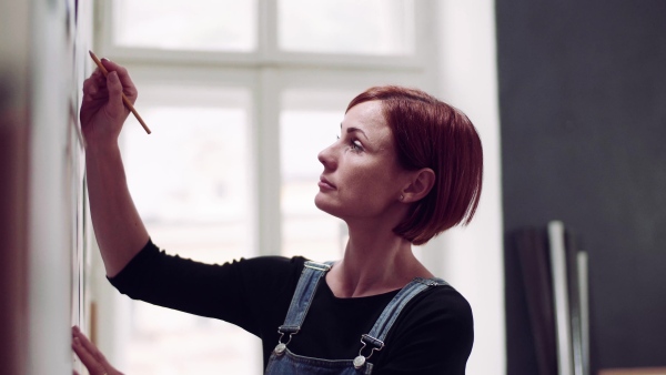 A young woman making plans for work indoors, writing on board.