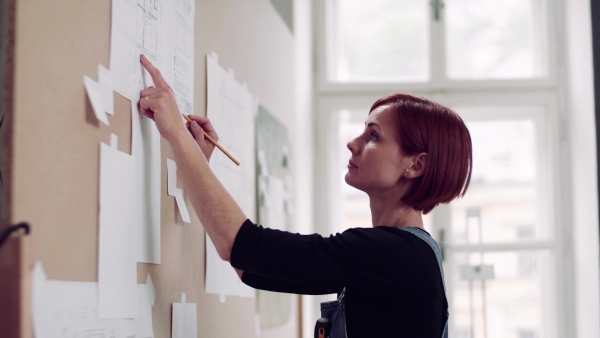 A young woman making plans for work indoors, writing on board.