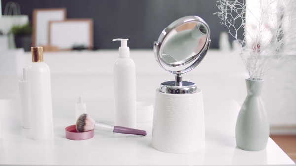 A close-up of mirror and beauty products on the desk.