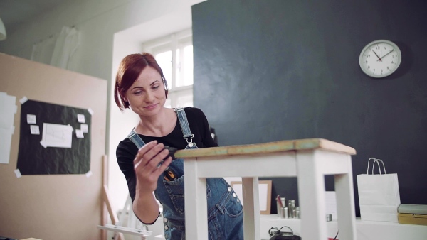 Young woman standing indoors restoring old furniture. Slow motion.