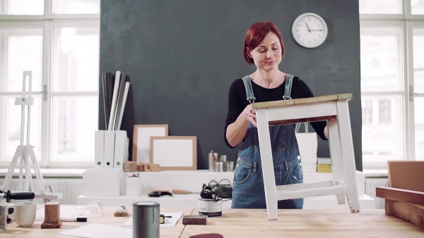 Young woman standing indoors restoring old furniture. Slow motion.