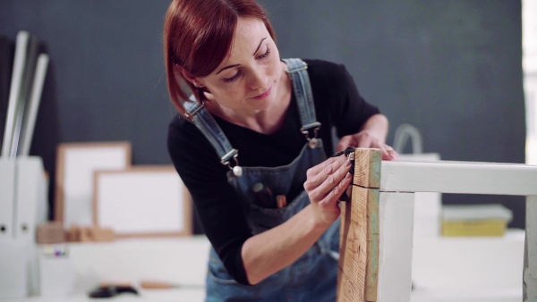 Young woman standing indoors restoring old furniture. Slow motion.