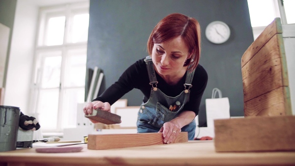 Young woman standing indoors restoring old furniture. Slow motion.