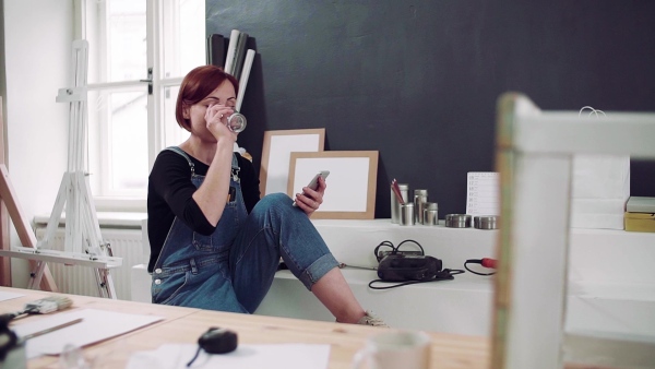 Young woman using smartphone indoors, old furniture restoration. Slow motion.