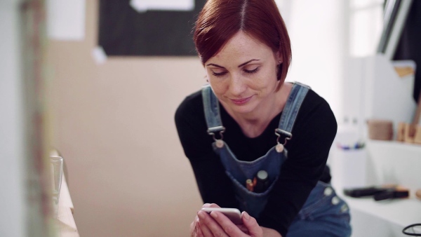 Young woman using smartphone indoors, old furniture restoration. Slow motion.