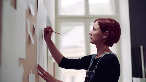 A young woman making plans for work indoors, writing on board. Slow motion.