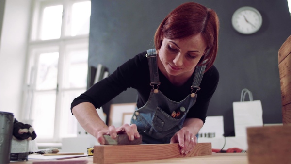 Young woman standing indoors restoring old furniture.