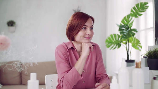 Young woman vlogger with beauty products indoors, sitting. Slow motion.