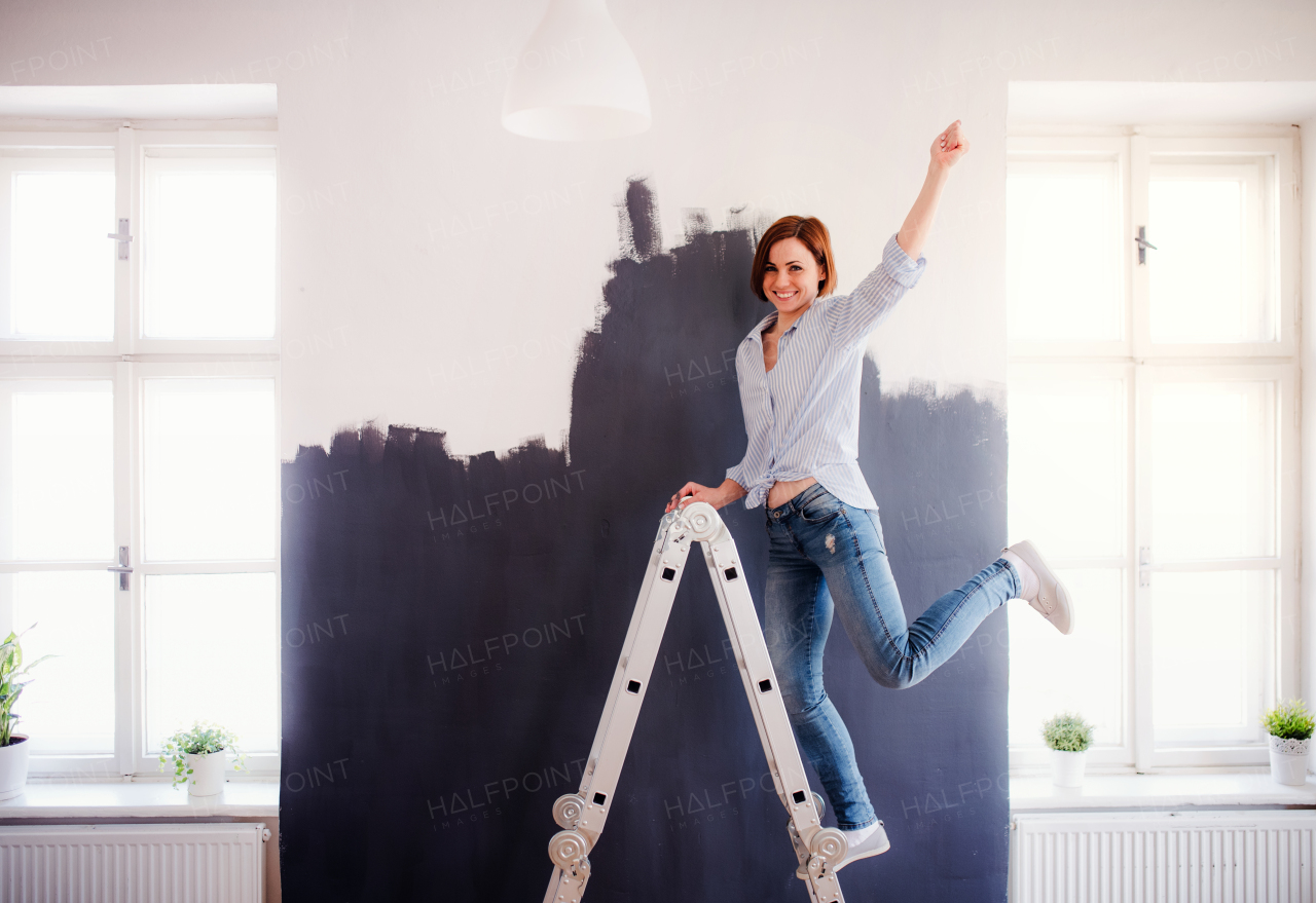 A portrait of young creative woman painting wall black. A startup of small business.