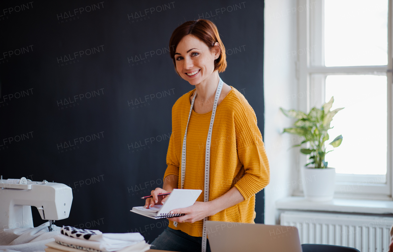 Young creative woman in a studio, writing. A startup of small tailoring business.